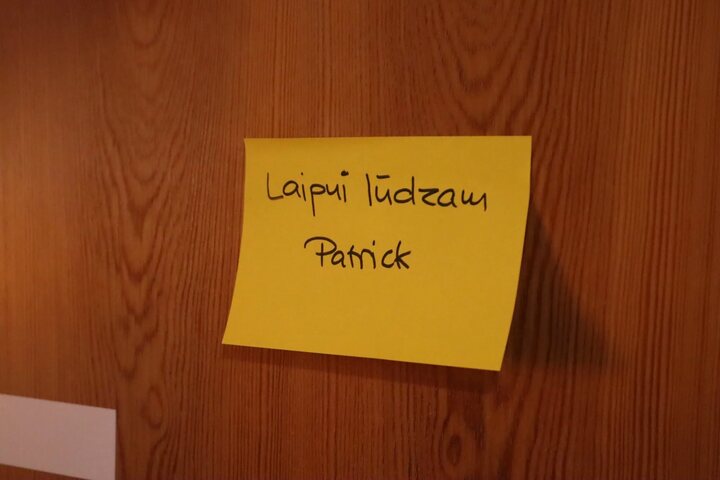 A handwritten welcome note on a yellow sticky note pinned to a door at the venue