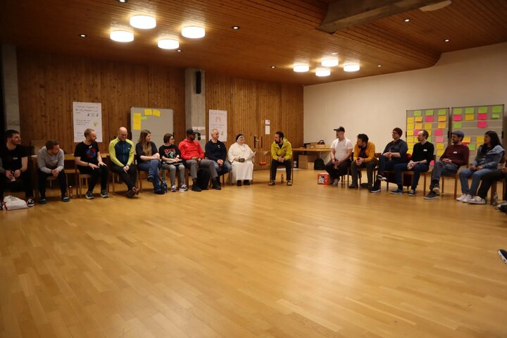 Participants sitting in a large circle in the wood-panelled hall during an open space session