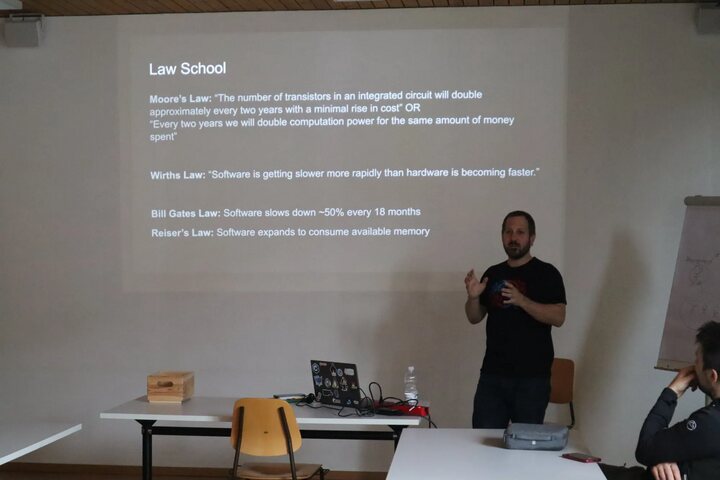 A speaker presenting a slide about Moore&rsquo;s Law and Wirth&rsquo;s Law during a session