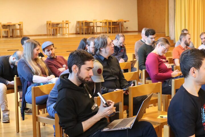 Attendees following a session, some taking notes on laptops